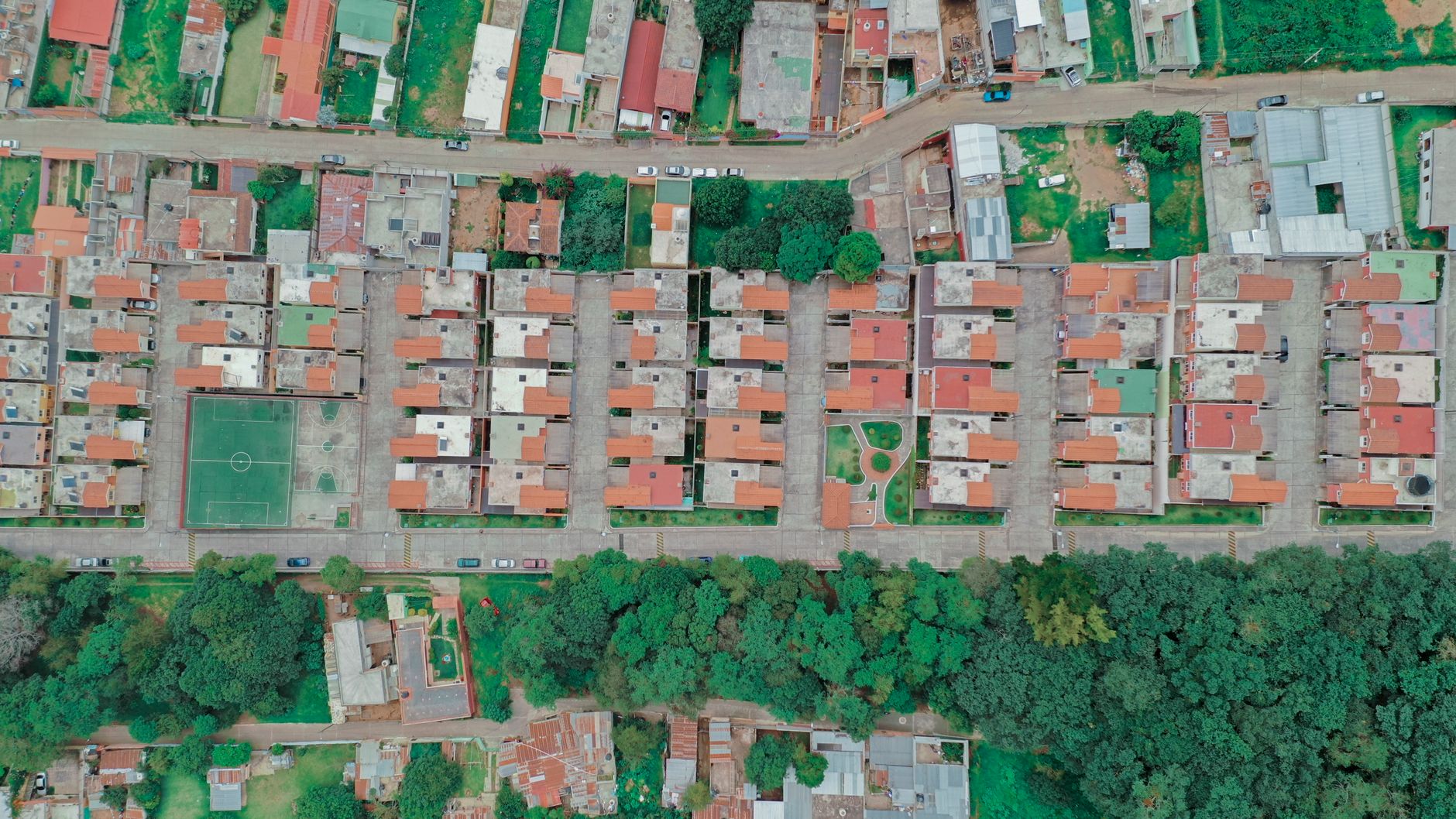 Toma de dron que captura un área residencial suburbana en Guatemala, mostrando techos vibrantes y vegetación.