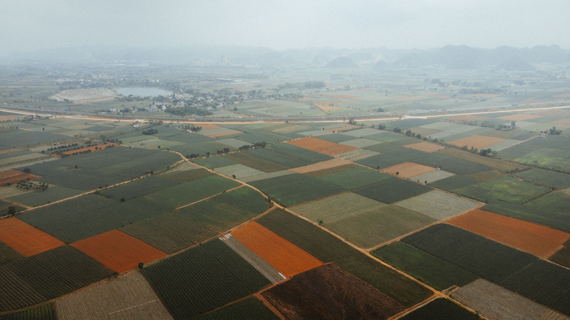 Aerial view showcasing vast agricultural fields with diverse crops and geometric patterns.